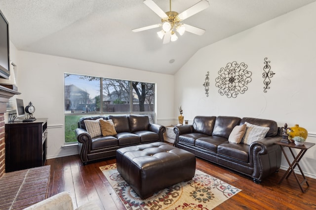 living area featuring a fireplace, wood-type flooring, a ceiling fan, baseboards, and vaulted ceiling