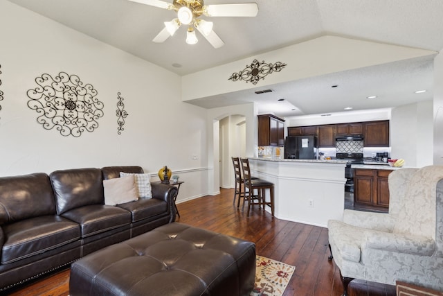living room with a ceiling fan, dark wood-style flooring, visible vents, arched walkways, and lofted ceiling