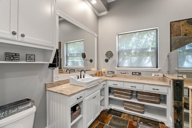 bathroom with vanity, toilet, crown molding, and stone tile flooring