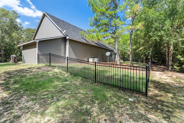 view of side of home with a yard, fence, and a shingled roof
