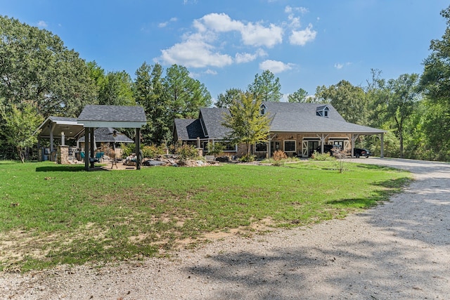 view of front facade with a carport, gravel driveway, and a front yard