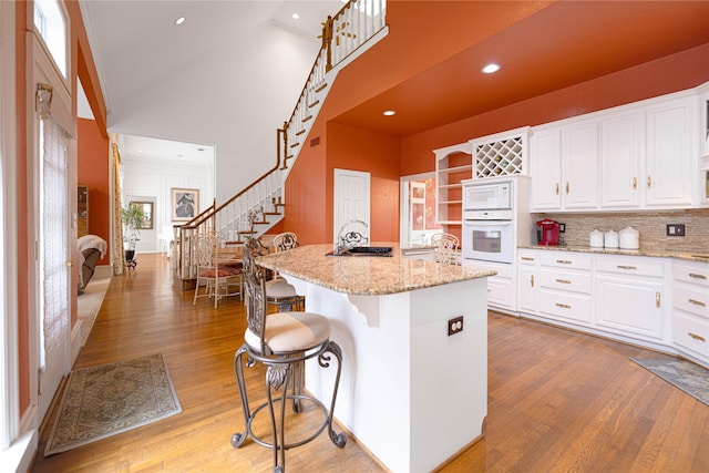 1204 Lakeridge Dr, Ennis, TX 75119 - kitchen with wood finished floors, a high ceiling, white cabinets, and white appliances