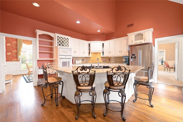 1204 Lakeridge Dr, Ennis, TX 75119 - kitchen featuring open shelves, white appliances, light wood-type flooring, white cabinetry, and light stone counters