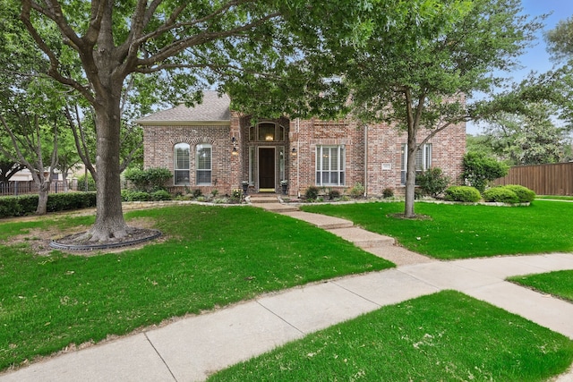 view of front of house featuring brick siding, a shingled roof, a front lawn, and fence