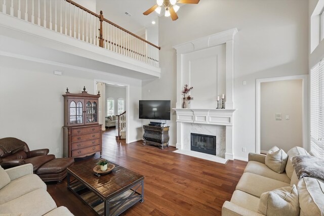 living room with a high ceiling, a ceiling fan, wood finished floors, and a wealth of natural light