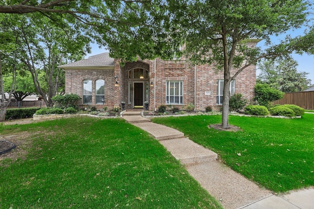 view of front of home with brick siding, fence, and a front lawn