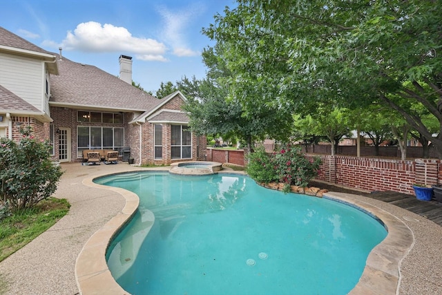 view of pool with fence, a patio, and a pool with connected hot tub