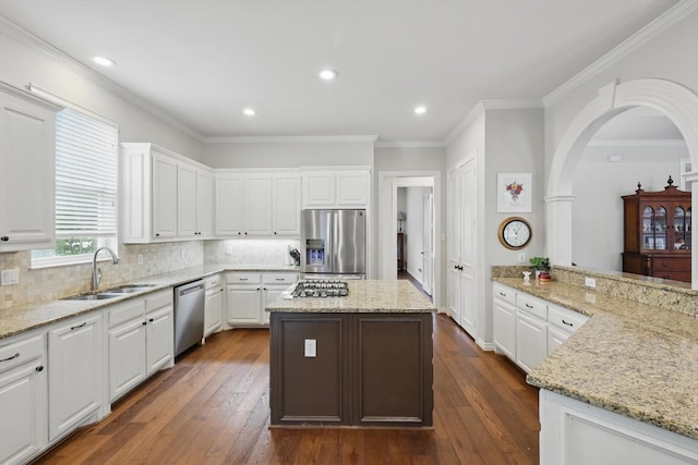 kitchen with white cabinets, appliances with stainless steel finishes, a sink, dark wood-type flooring, and ornamental molding
