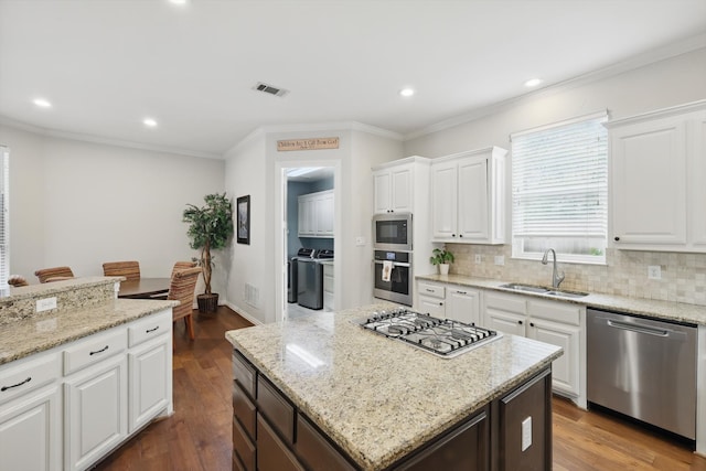 kitchen with visible vents, washing machine and clothes dryer, tasteful backsplash, a sink, and appliances with stainless steel finishes