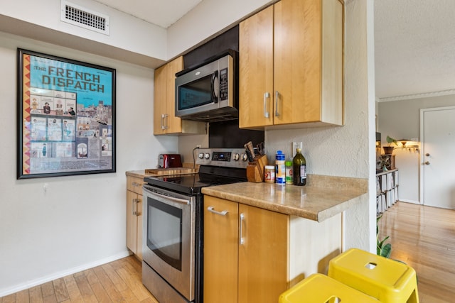 kitchen featuring stainless steel appliances, light wood-type flooring, visible vents, light countertops, and baseboards