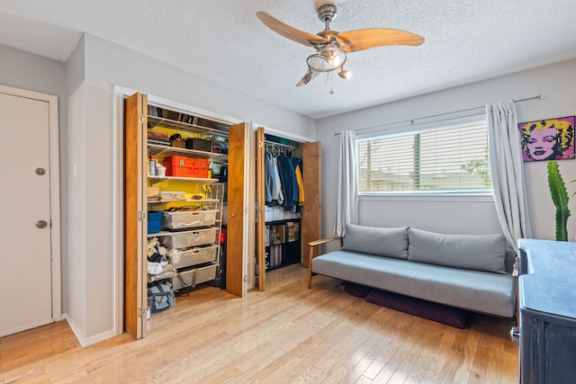 bedroom with light wood finished floors, a textured ceiling, a ceiling fan, and multiple closets