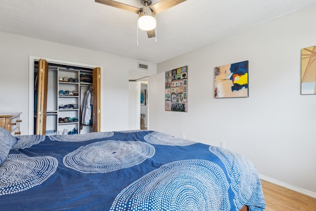 bedroom with a ceiling fan, a closet, baseboards, visible vents, and wood finished floors