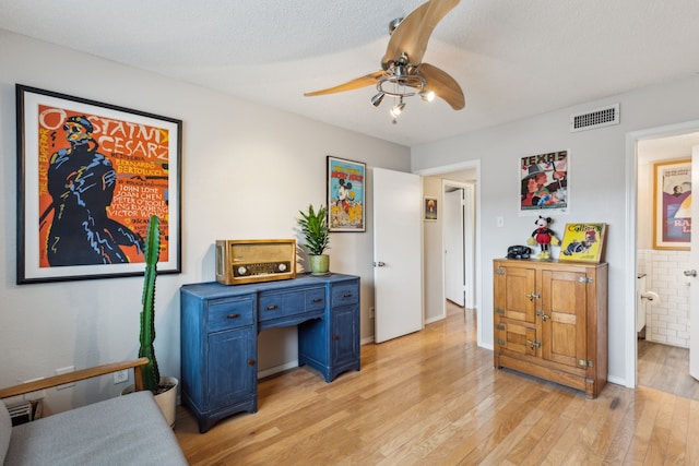 home office with light wood-style flooring, a ceiling fan, and visible vents