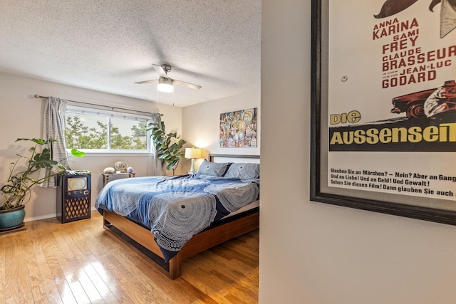 bedroom featuring a textured ceiling, wood finished floors, baseboards, and ceiling fan