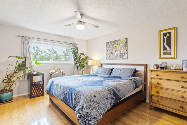 bedroom with a textured ceiling, baseboards, a ceiling fan, and wood finished floors
