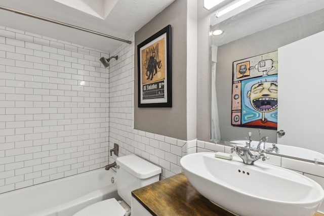 full bath featuring toilet, shower / bath combination, tile walls, and a sink