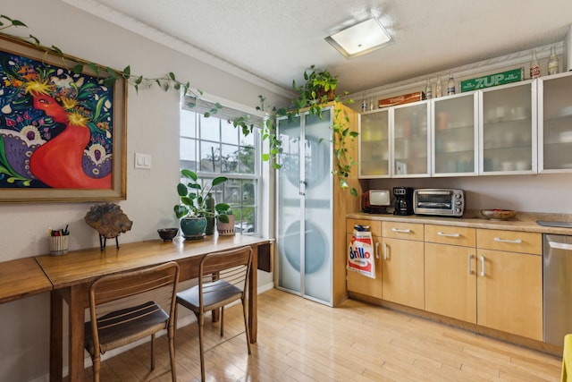 kitchen featuring light countertops, light wood-type flooring, glass insert cabinets, and dishwasher