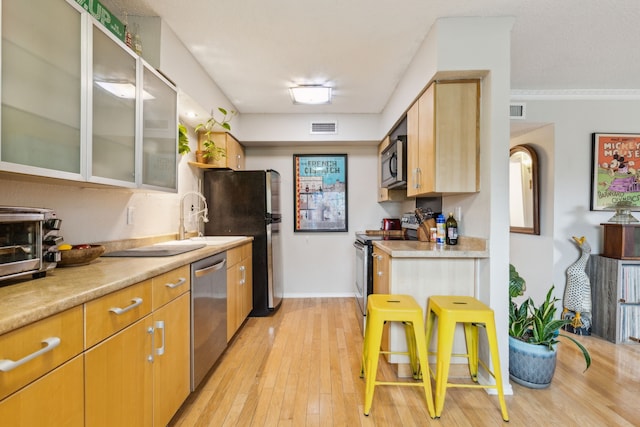 kitchen with light countertops, appliances with stainless steel finishes, visible vents, and light wood-type flooring
