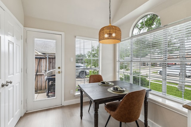 dining space with baseboards, lofted ceiling, a healthy amount of sunlight, and light wood finished floors