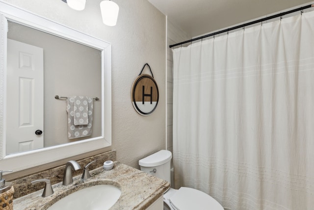 full bath featuring vanity, a textured wall, curtained shower, and toilet