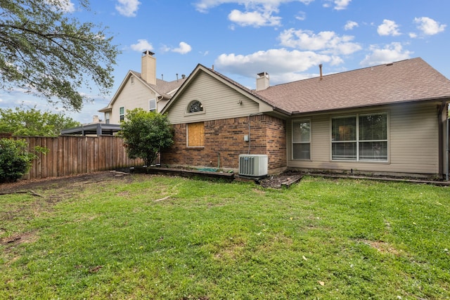 back of property with a chimney, a lawn, brick siding, fence, and a shingled roof