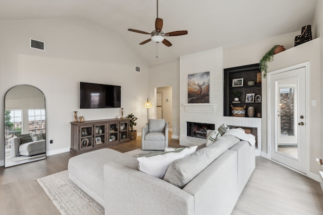 living room with a ceiling fan, visible vents, wood finished floors, and a fireplace