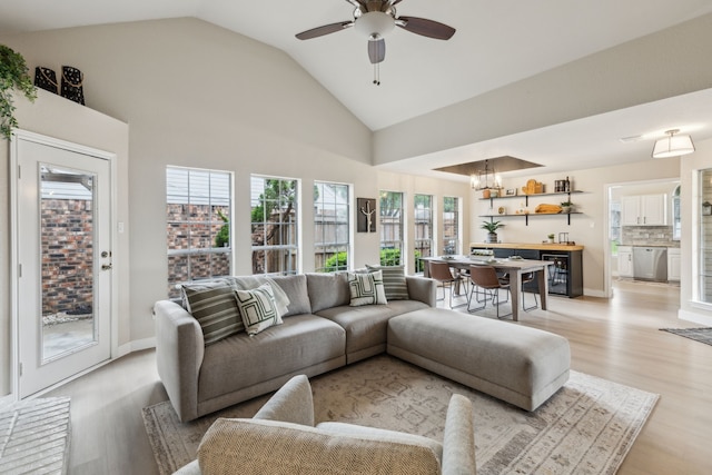 living area featuring light wood-style flooring, ceiling fan with notable chandelier, and lofted ceiling