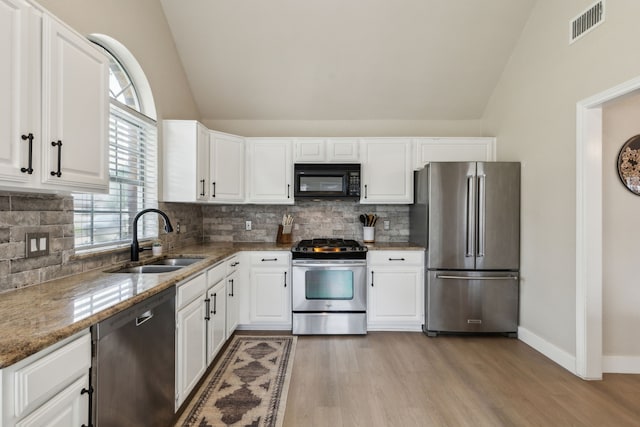 kitchen featuring visible vents, appliances with stainless steel finishes, a sink, light stone counters, and light wood-style floors