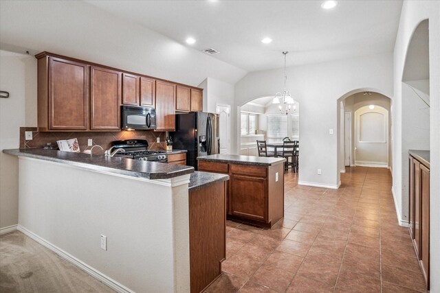 kitchen with visible vents, dark countertops, arched walkways, black appliances, and lofted ceiling