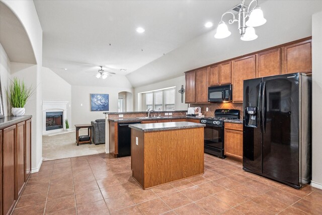 kitchen featuring dark countertops, a center island, brown cabinets, ceiling fan with notable chandelier, and lofted ceiling