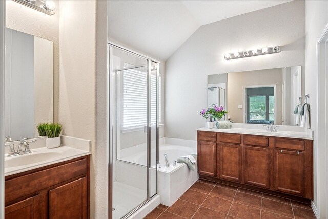full bathroom featuring vaulted ceiling, vanity, a shower stall, and a garden tub