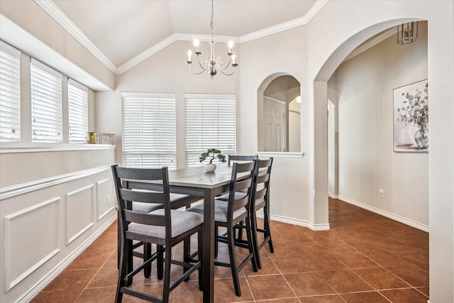 dining room featuring a notable chandelier, arched walkways, dark tile patterned flooring, vaulted ceiling, and ornamental molding