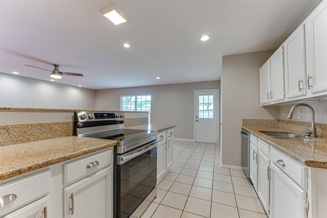 kitchen with baseboards, white cabinets, a sink, light tile patterned floors, and stainless steel appliances
