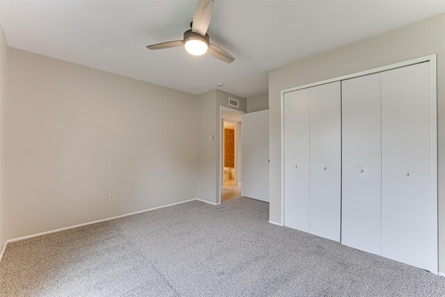 unfurnished bedroom with baseboards, ceiling fan, carpet, and a closet