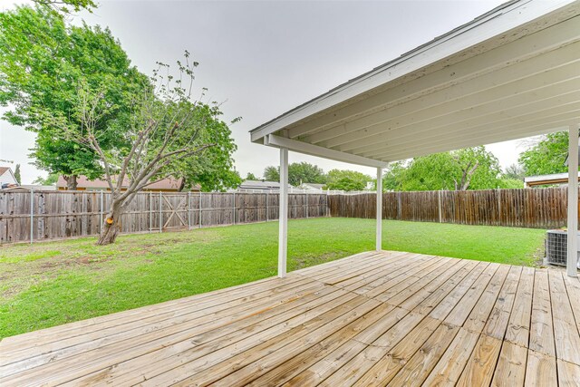 wooden terrace featuring a lawn, a fenced backyard, and cooling unit