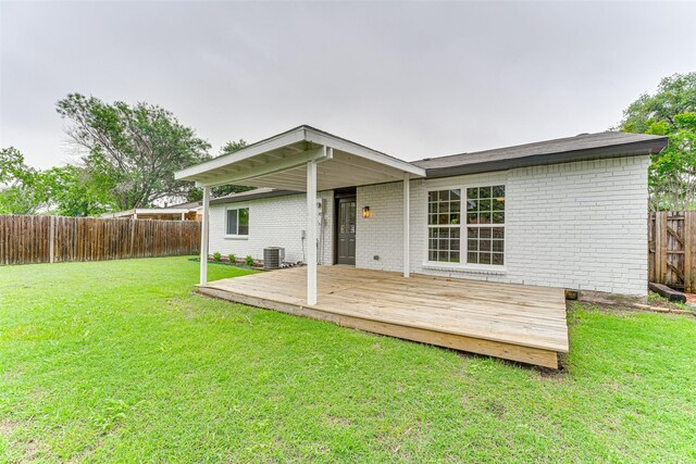 back of house featuring a lawn, brick siding, a wooden deck, and a fenced backyard