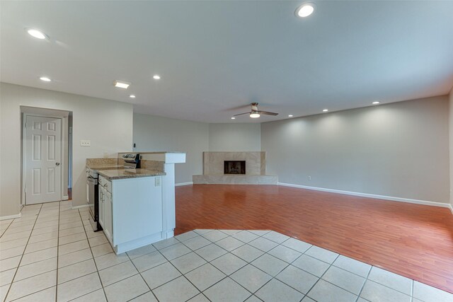 kitchen with ceiling fan, light stone counters, light wood-style floors, recessed lighting, and baseboards