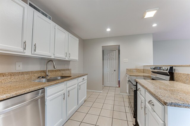 kitchen featuring appliances with stainless steel finishes, a sink, light tile patterned floors, recessed lighting, and white cabinetry