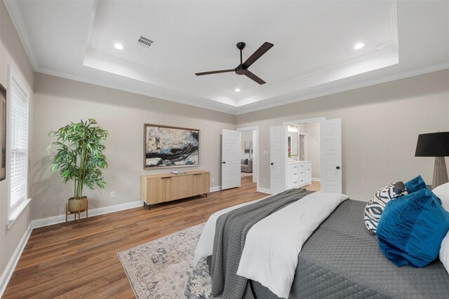 bedroom with crown molding, visible vents, wood finished floors, and a raised ceiling