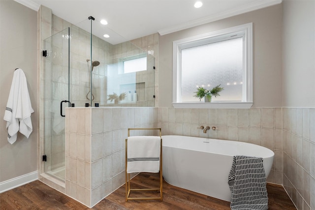 bathroom featuring crown molding, tile walls, a stall shower, wood finished floors, and a soaking tub