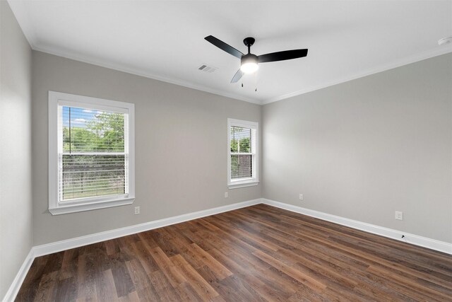 empty room featuring a ceiling fan, visible vents, crown molding, dark wood finished floors, and baseboards