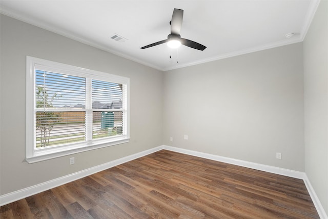 spare room with visible vents, ornamental molding, baseboards, and dark wood-style flooring