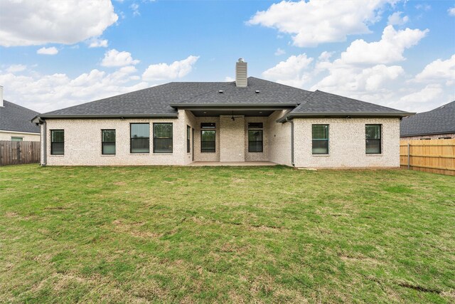 rear view of house with a fenced backyard, a patio, a chimney, and a yard