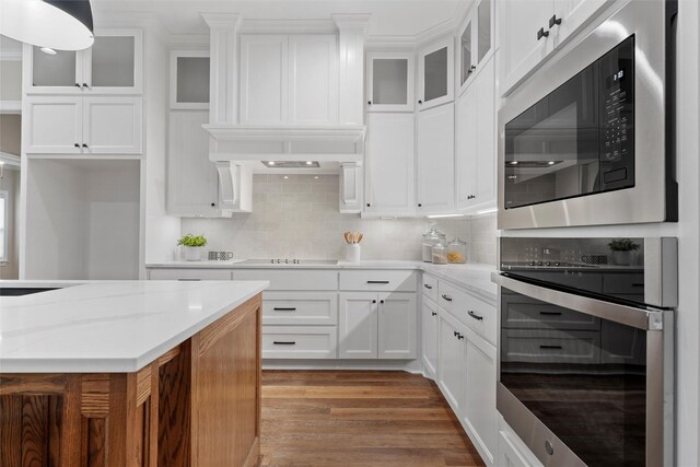 kitchen featuring light wood finished floors, built in microwave, white cabinetry, and oven