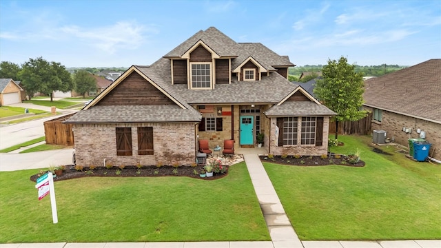 craftsman-style house featuring brick siding, central AC, fence, a front lawn, and a shingled roof