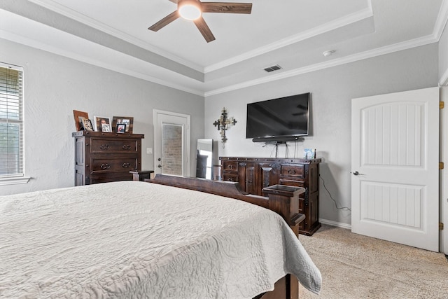 bedroom featuring light colored carpet, crown molding, a tray ceiling, and visible vents
