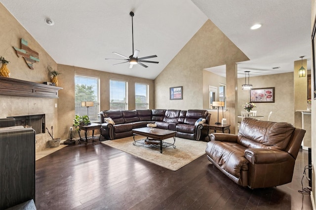 living room with a ceiling fan, high vaulted ceiling, a tiled fireplace, and hardwood / wood-style floors