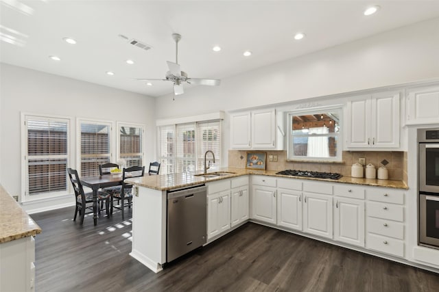 16114 Shadybank Dr, Dallas, TX 75248 - kitchen featuring dark wood-style flooring, tasteful backsplash, a sink, a peninsula, and stainless steel appliances
