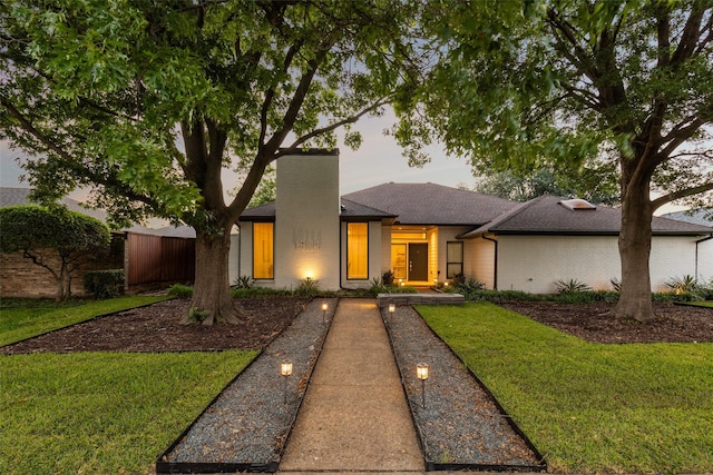 16114 Shadybank Dr, Dallas, TX 75248 - view of front facade featuring roof with shingles, a chimney, a front lawn, and brick siding
