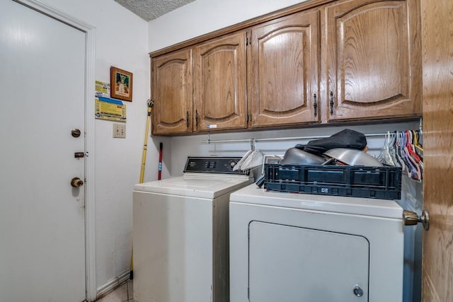 clothes washing area with separate washer and dryer and cabinet space